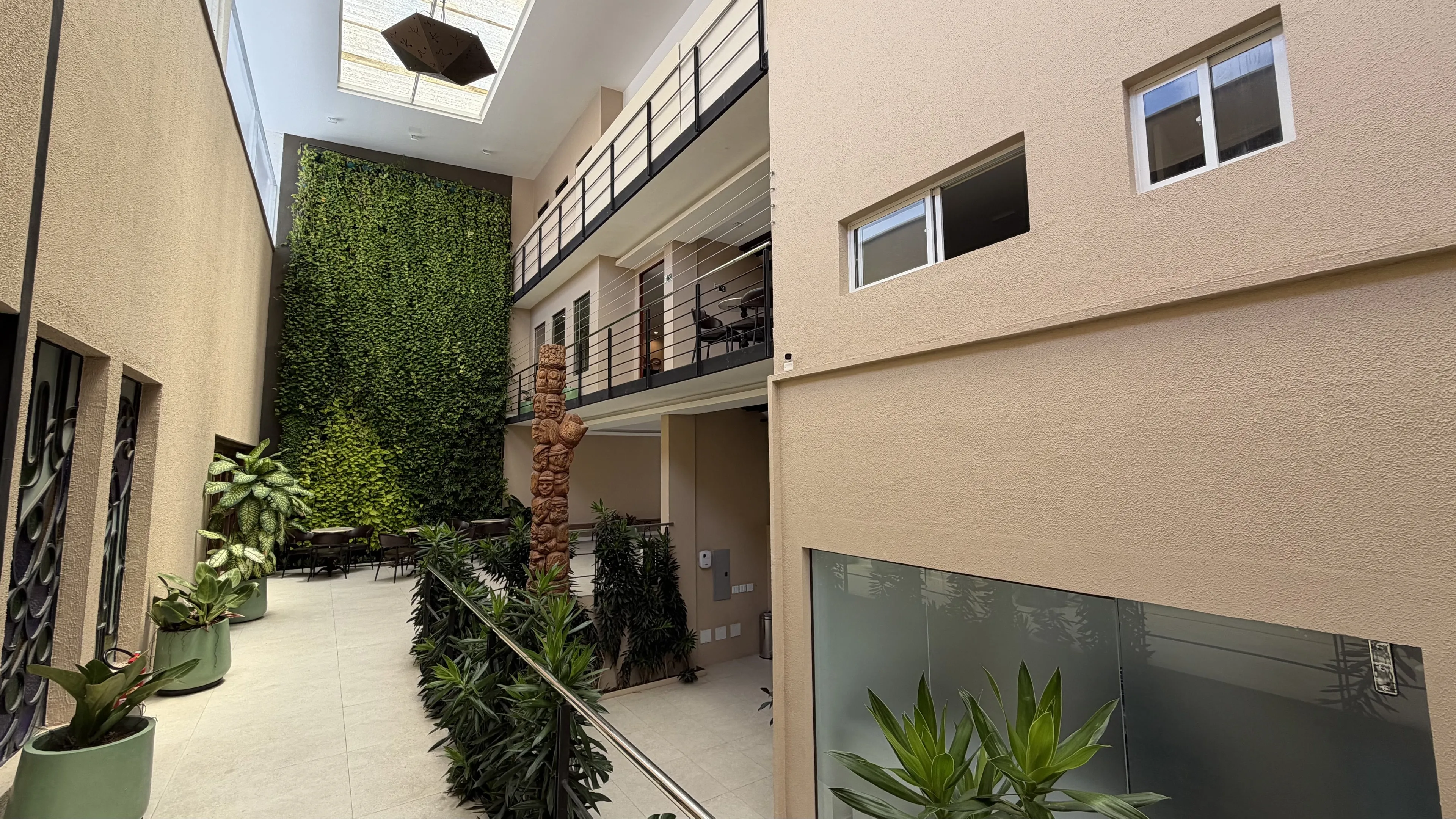 Área de circulação com pé-direito duplo, jardim vertical, passarelas e plantas
