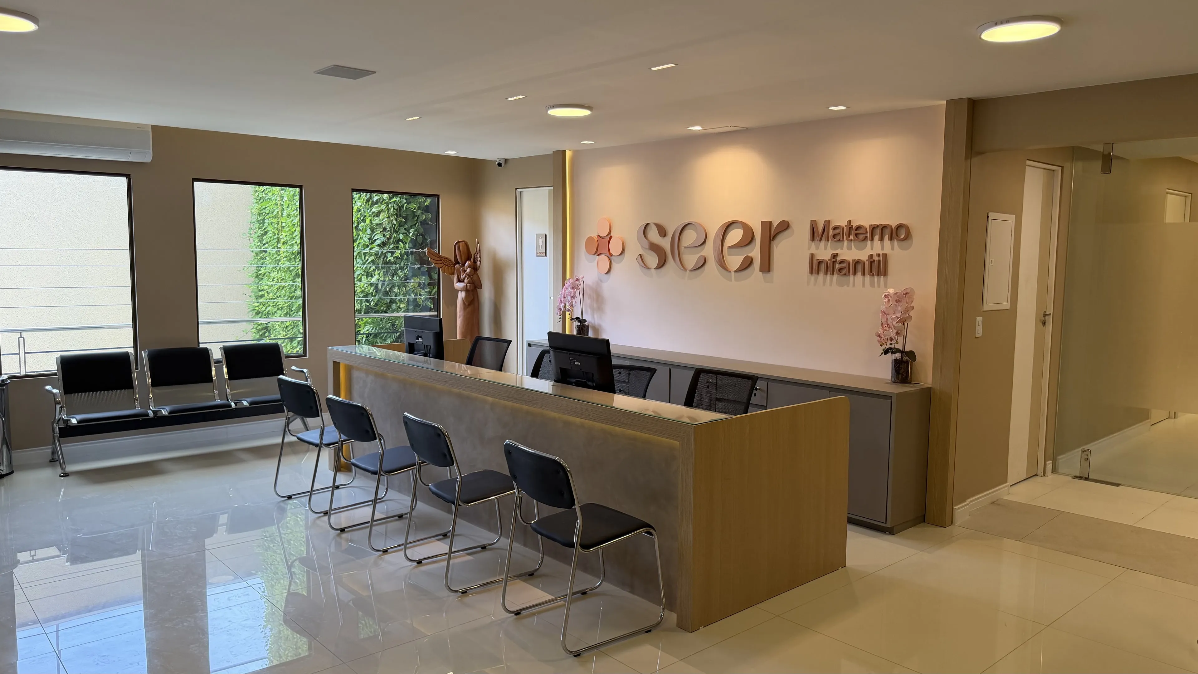 Recepção Materno-Infantil da SEER Saúde com balcão de atendimento, letreiro “seer Materno Infantil” e longarinas